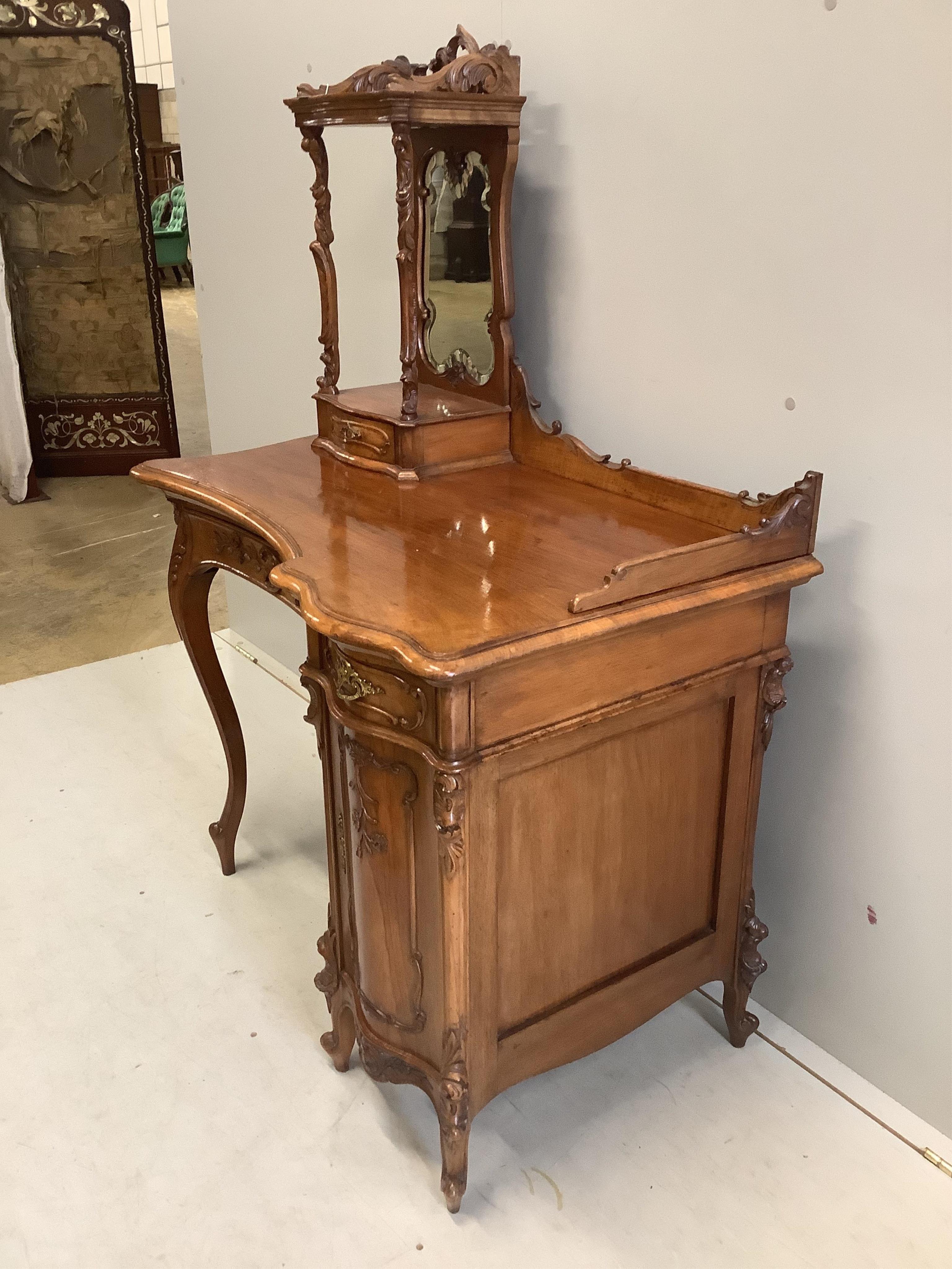 A Continental Art Nouveau carved walnut dressing table, width 92cm, depth 56cm, height 134cm. Condition - fair to good